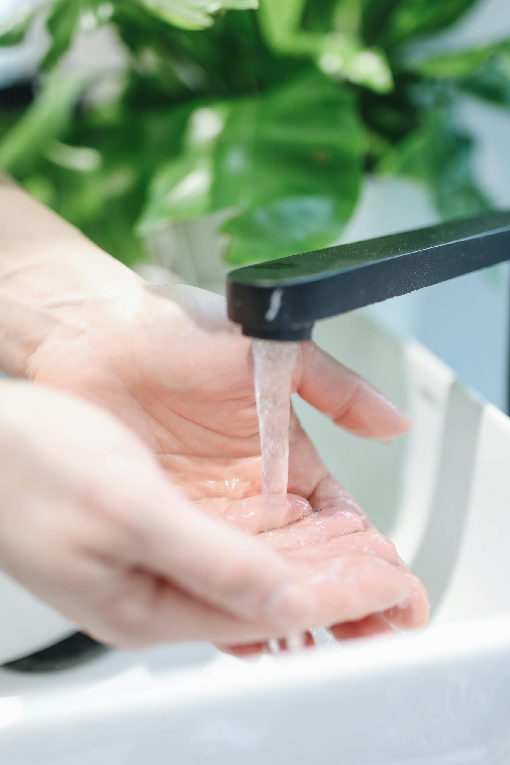 A close-up shot of hands being washed under a modern faucet indoors.