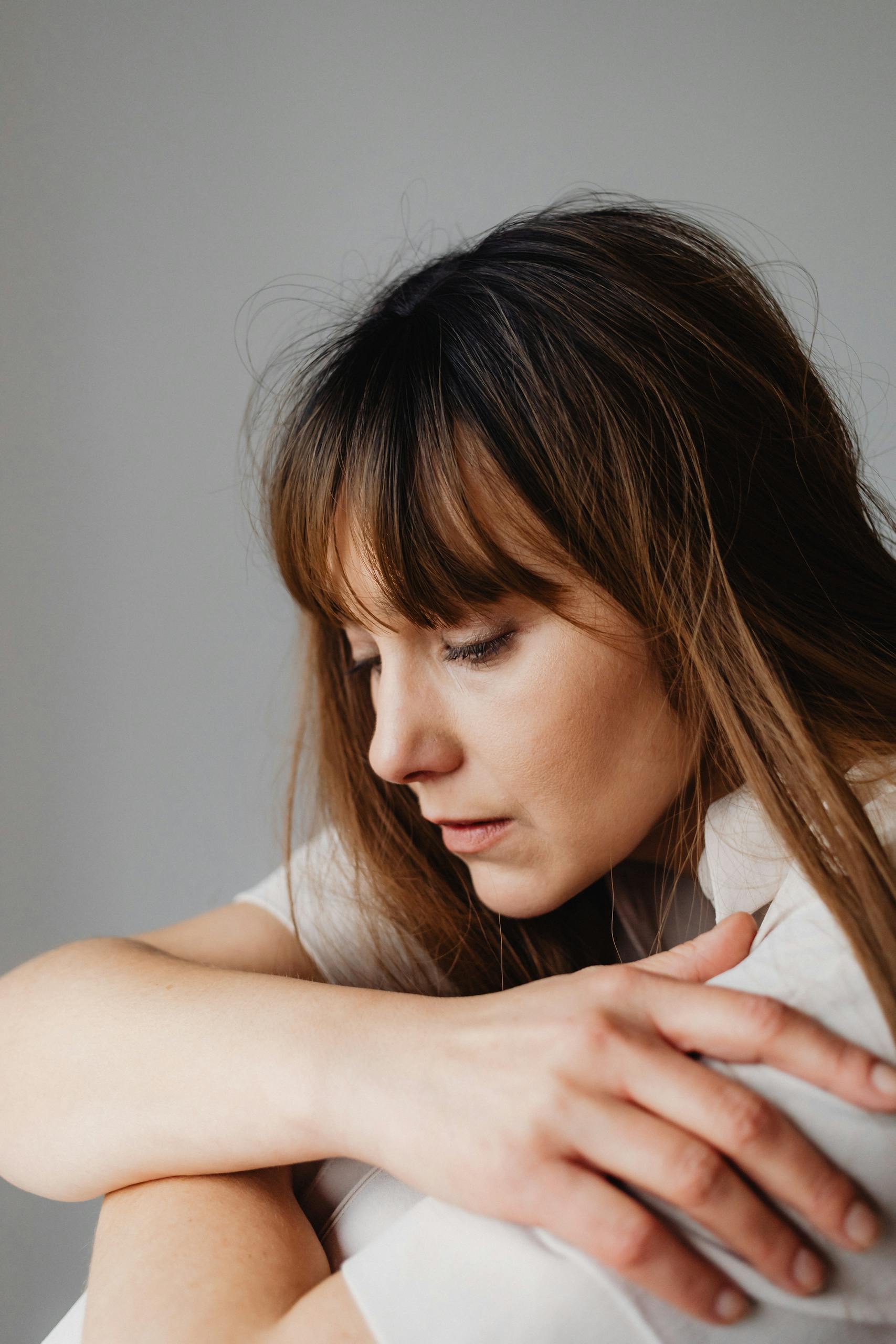 A serene portrait of a woman lost in thought, captured indoors in natural light.