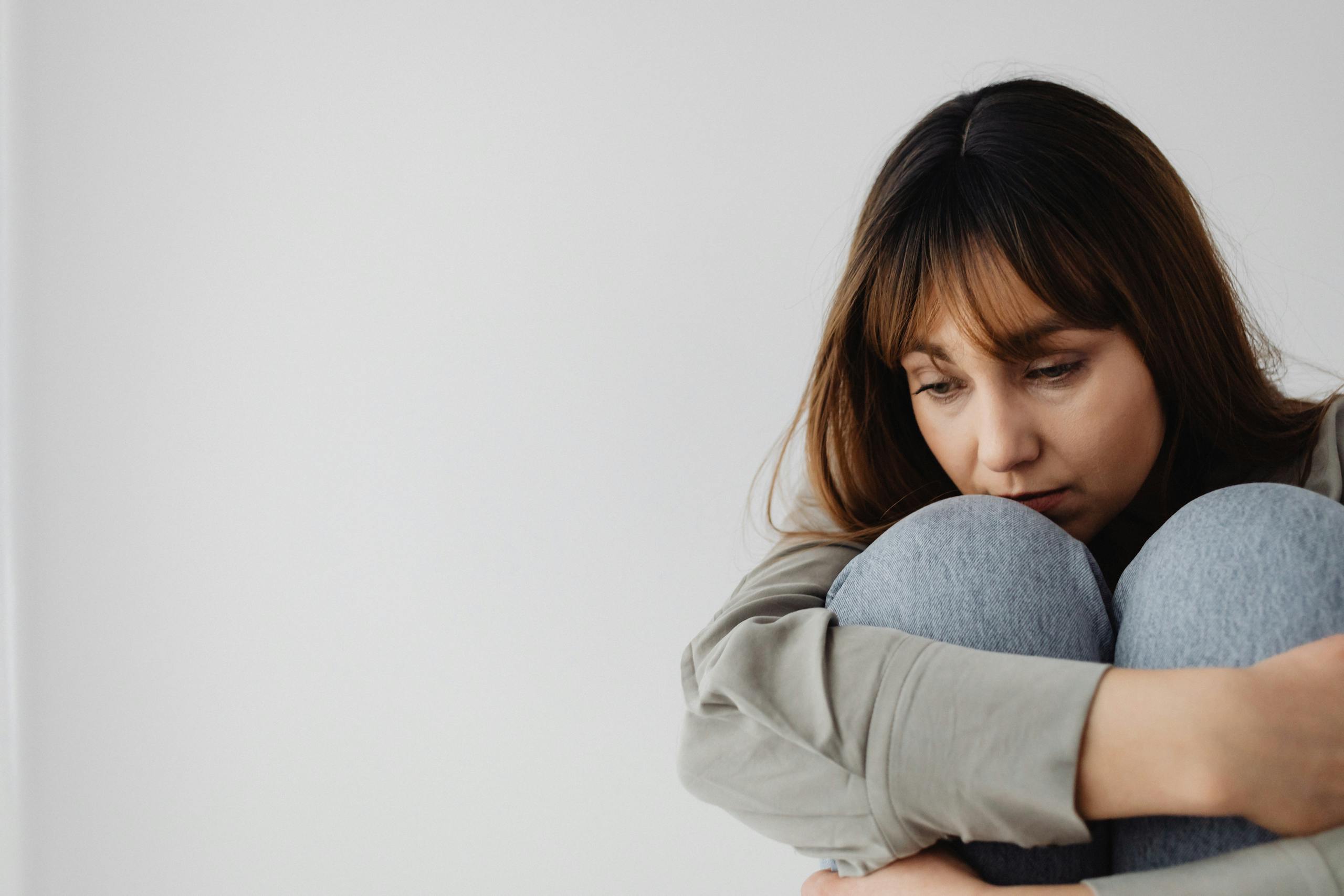 Caucasian woman sitting pensively indoors, capturing a moment of reflection and emotion.